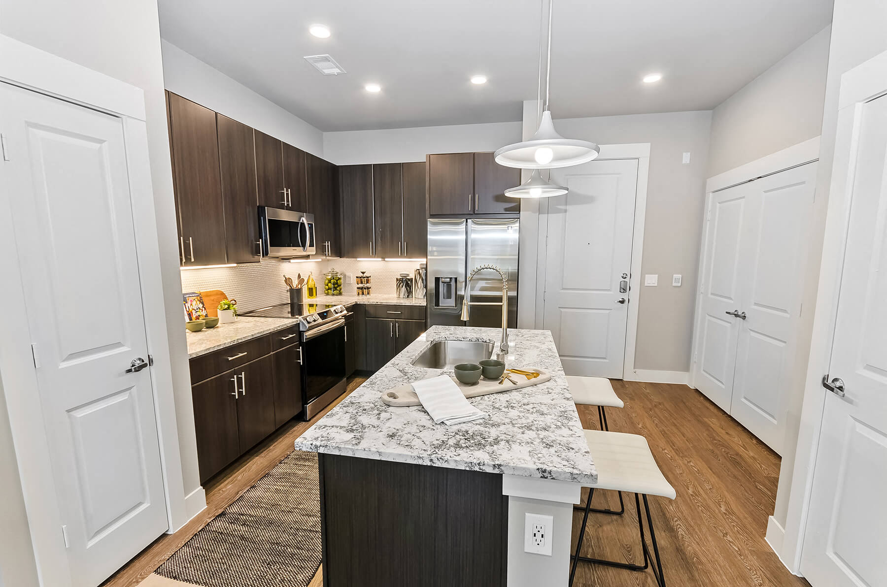 A modern kitchen with dark cabinets with a kitchen island at the Opal Legacy Central in Plano, Texas.